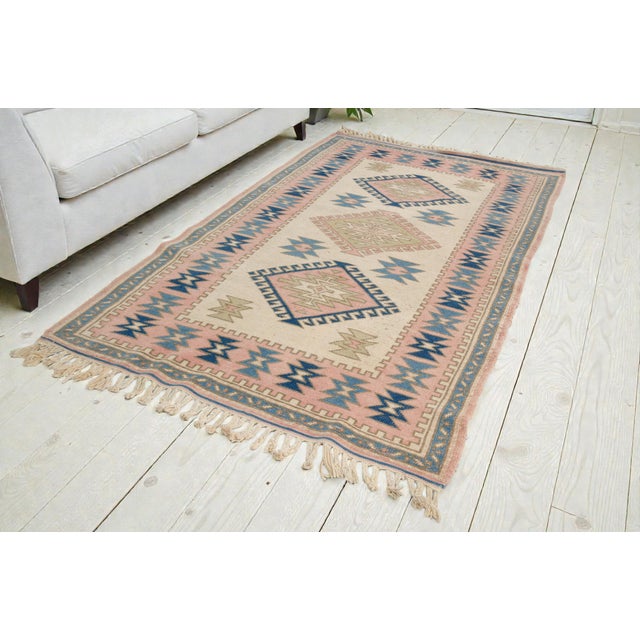This is a vintage Turkish Oushak rug from the Mid 20th Century. The piece was hand-knotted.