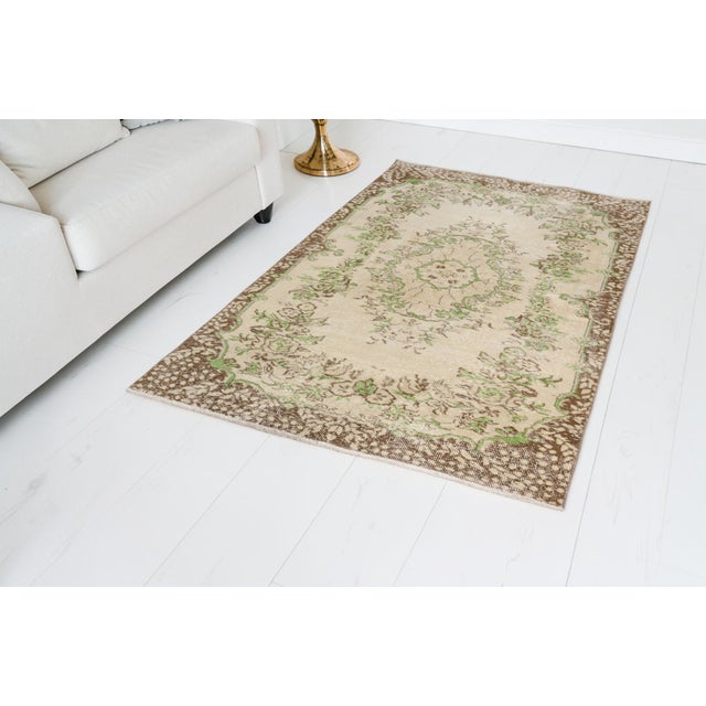This is a vintage Turkish Oushak rug from the Mid 20th Century. The piece was hand-knotted.