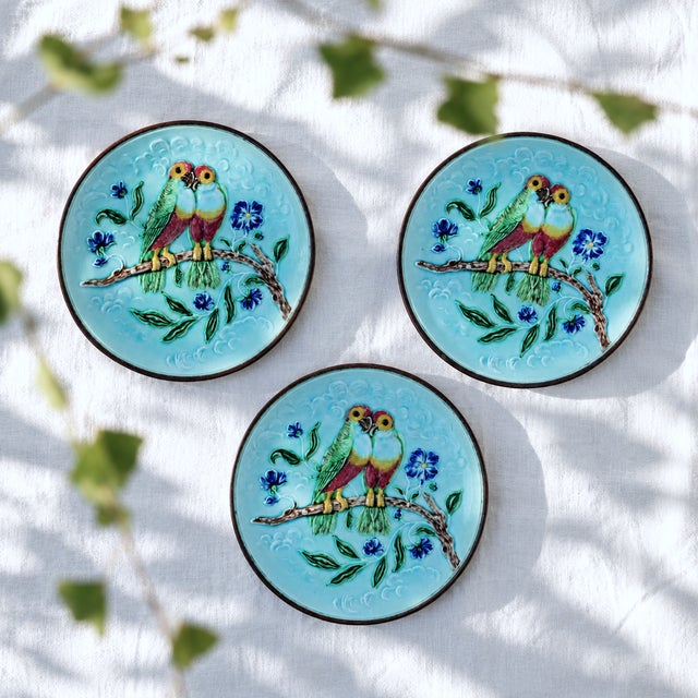 A set of three rare and lovely majolica-barbotine plates decorated with a charming relief design depicting a pair of...