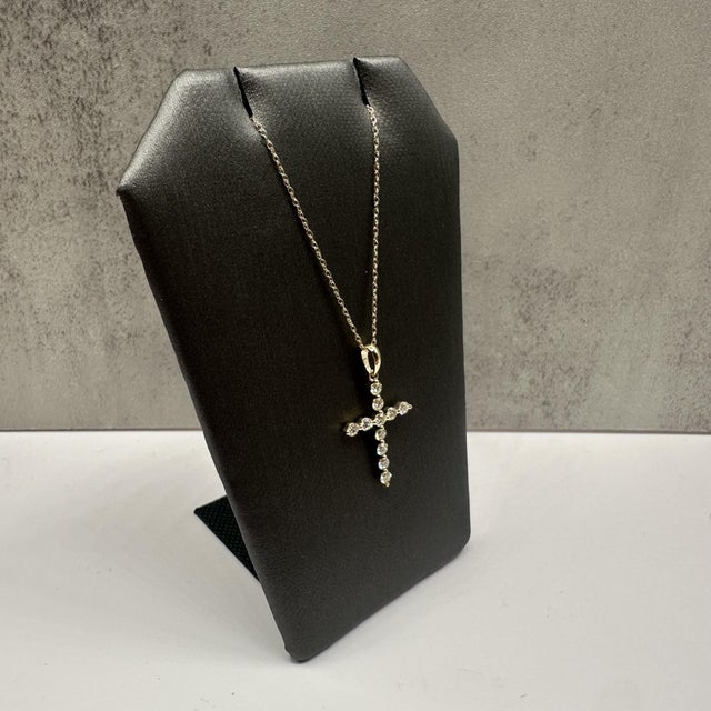 This elegant natural diamond cross necklace in 10kt yellow gold features 0.45 carats total weight of natural IJ SI round...
