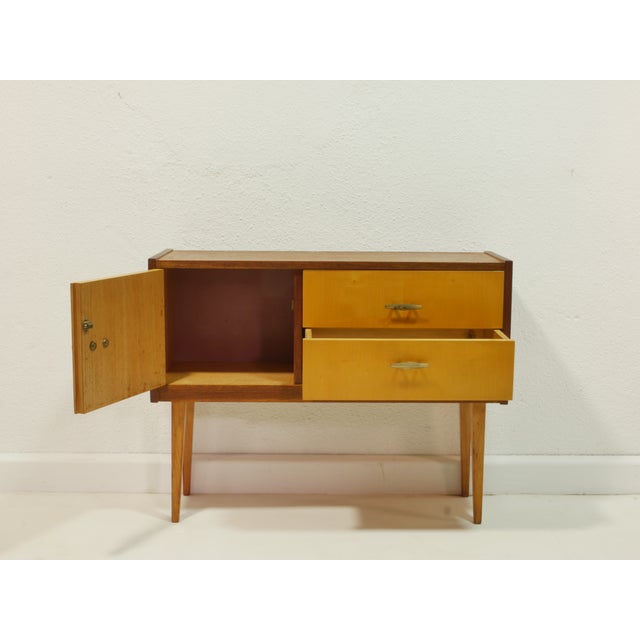 This charming vintage chest of drawers from the 1960s impresses with its clean, mid-century design and warm combination of...