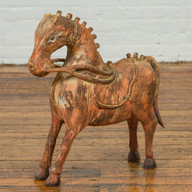 A small Indian vintage carved and rust colored wooden horse sculpture from Madras with distressed patina. Born in the...