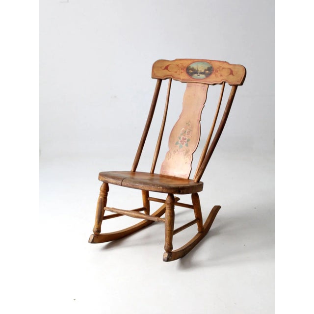 This antique rocking chair features a graceful fiddleback silhouette with a hand-painted landscape motif adorning the...