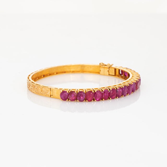 Stylish vintage ruby bangle bracelet crafted in 18 karat yellow gold. Oval faceted rubies measure approx. 5mm x 4.5mm...