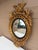 An antique Federal or Regency style giltwood convex mirror crowned with a carved eagle, its wings outstretched above a...