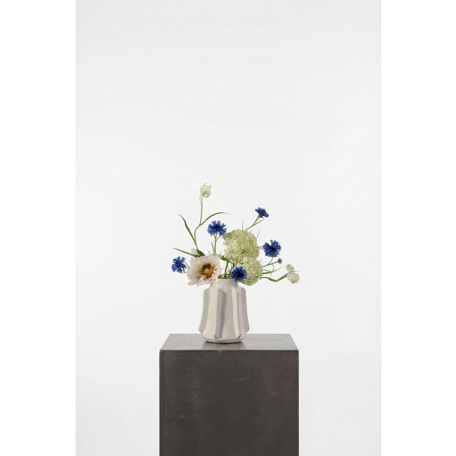 A fresh, textural mix of blue cornflower, cream poppy, and soft green snowball. The contrast between crisp whites and...