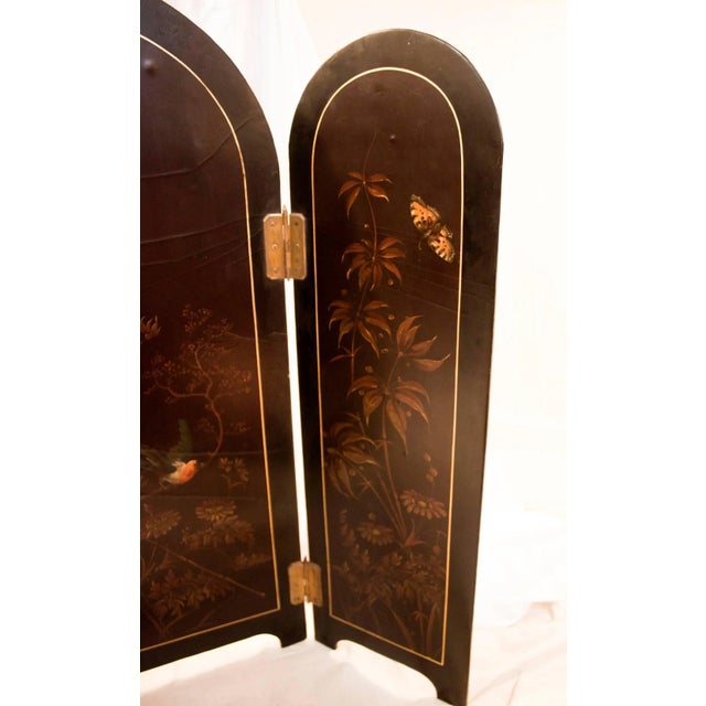 Unusual small size papier mache tabletop screen featuring hand painted flowers, a colorful bird and butterfly. Three brass...