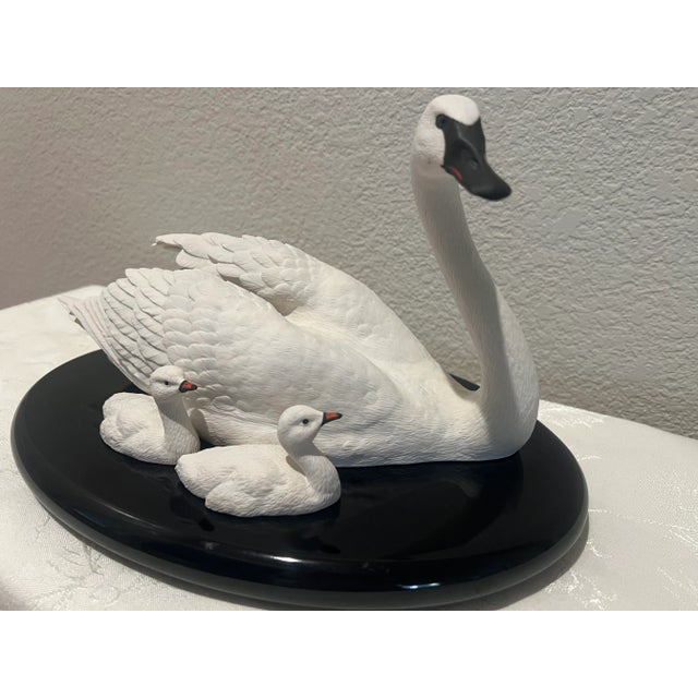Handsome piece that depicts 3 White Swans on an oval Black pedestal. The momma and 2 baby swans are created from porcelain...
