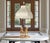 This vintage Neoclassical table lamp features two elegant female figurines cast in fine white glazed porcelain,...
