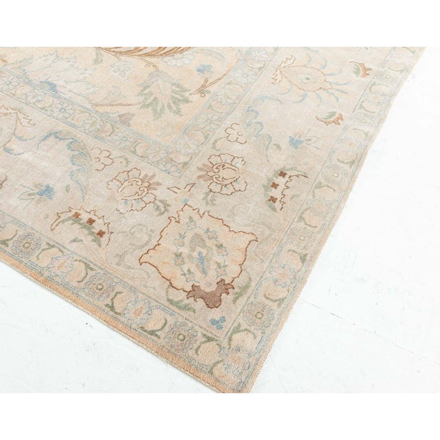 An early 20th century antique Tabriz Persian rug features intricate botanic design. The beige field with a subtle allover...