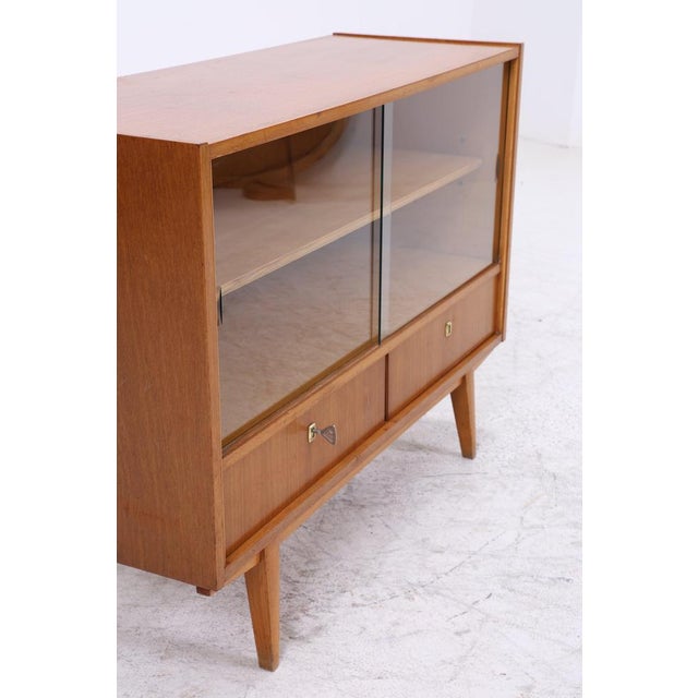 Vintage 1960s chest of drawers with clean lines and beautiful veneer grain. The combination of a glazed display area and...