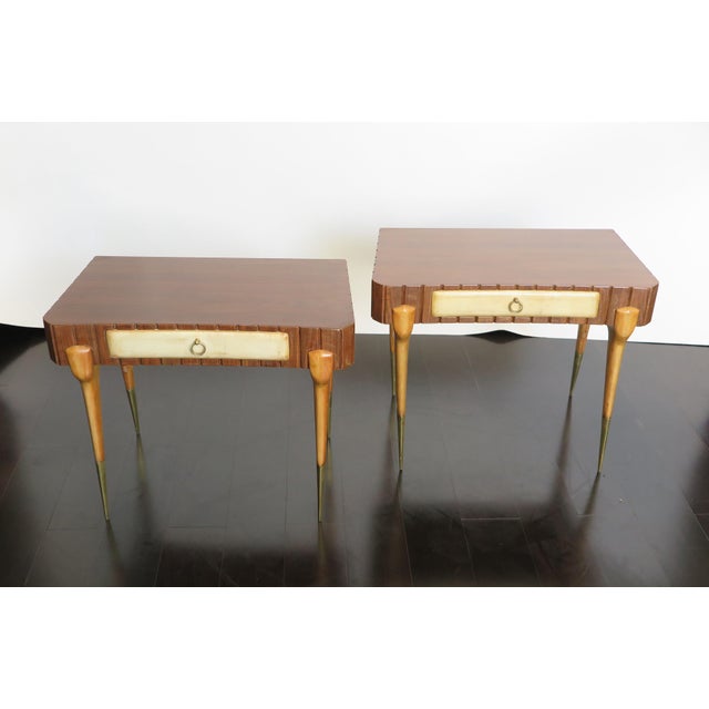 Pair of Mid-Century nightstands in rosewood with a parchment drawer. The thin tapered wooden legs feature a brass foot...