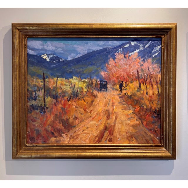 This oil painting captures a nostalgic scene of a dirt road winding through a vibrant autumn landscape, where warm hues of...