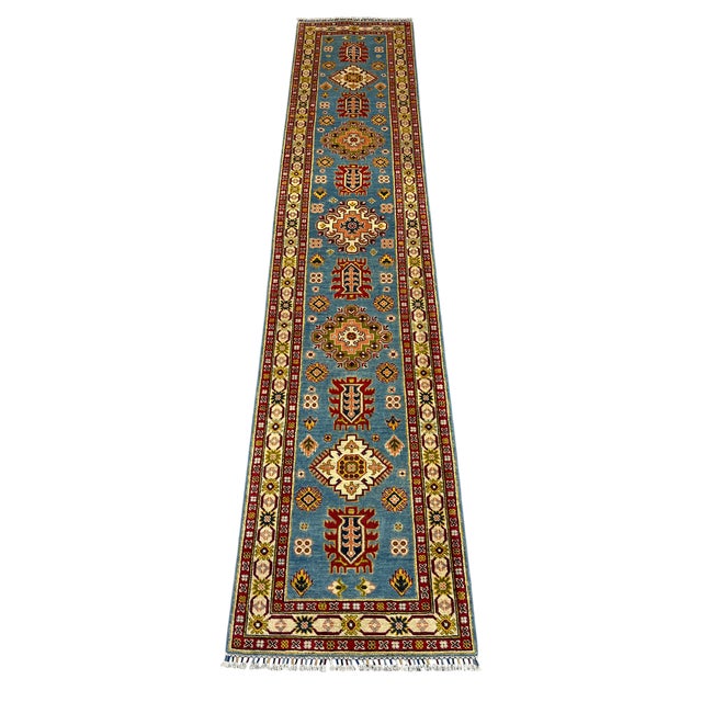 This long Kazak-style wool runner features a blue field with a row of bold tribal medallions. Burgundy and cream borders...