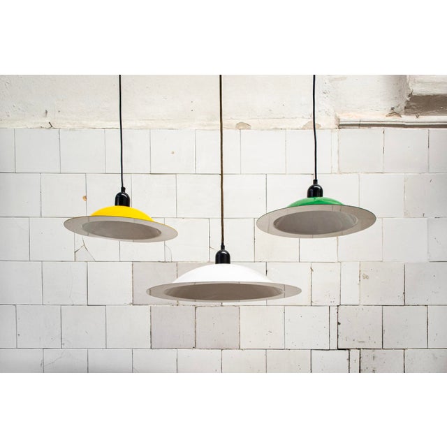 Pendant lamps in green, yellow, and white enameled metal. Model: Lampiatta Designed by Jonathan De Pas, Donato D'Urbino,...