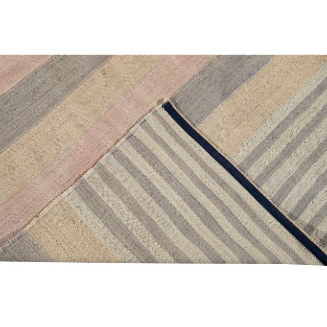 Beautiful modern flat-weave Kilim hand-knotted wool rug. This rug has a field of peach, pink, and gray color in a gorgeous...