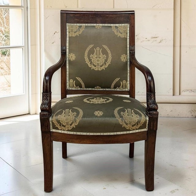 A refined 19th century French Empire period armchair, handcrafted in richly toned mahogany with the disciplined...