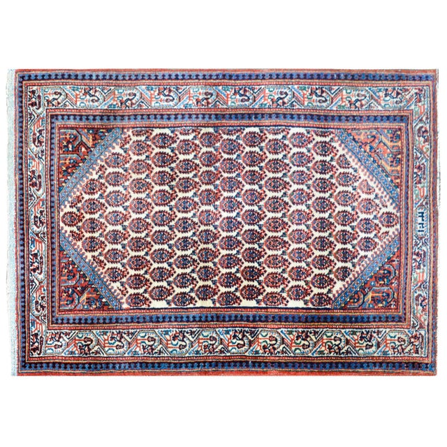 A charming early 20th century Persian Seraband rug with an all-over paisley pattern woven in crimson, and light and dark...