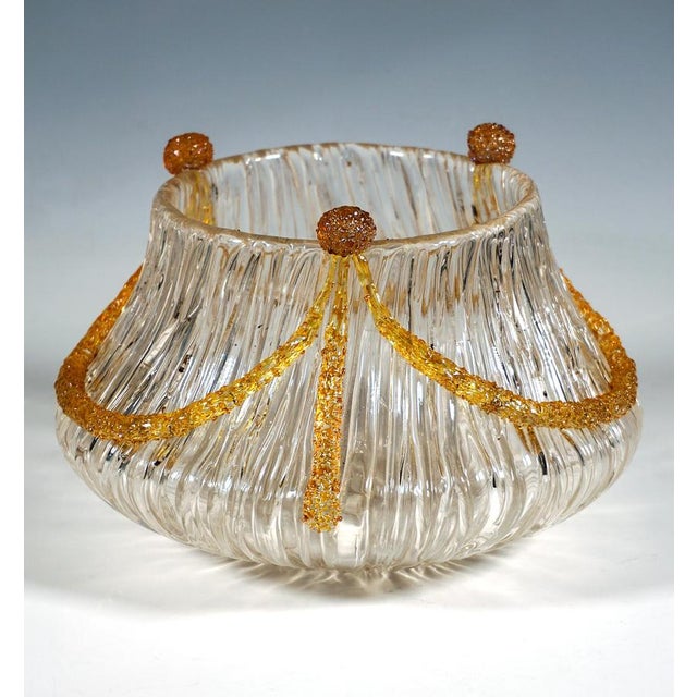 Mould-blown colourless glass with a wavy wall that widens flatly and bulbously at a flush base before curving inwards...