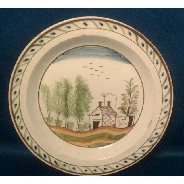 A fine and rare 18th c. English pearlware plate decorated with a landscape scene showing trees, a cottage and birds in the...