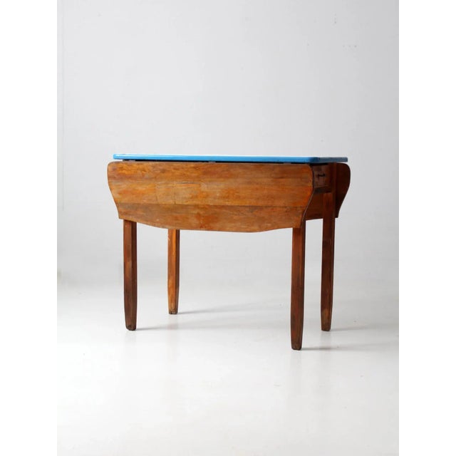 A vintage Napanee kitchenette table by Coopes Brothers & Zook, dating circa 1913–1935. The wooden drop-leaf table features...
