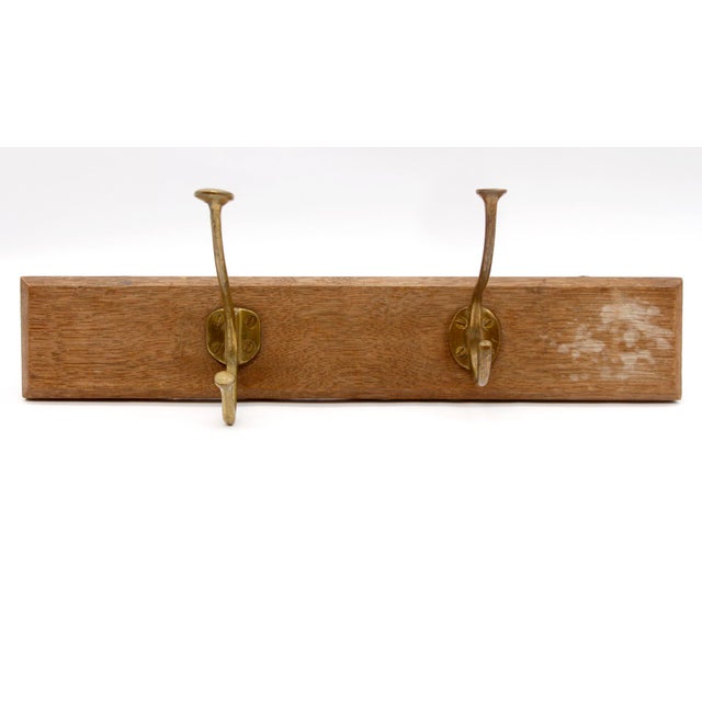 European wood plank with two mismatched brass hooks. The manufacturer and exact date of creation are unknown. This item...