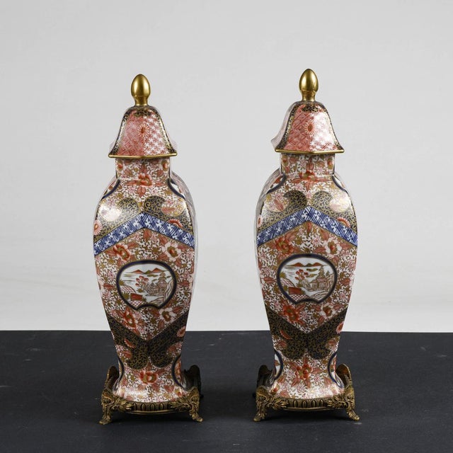 Pair of chinese ceramic potiche vases with worked metal base, richly decorated with oriental graphics in bright blue,...