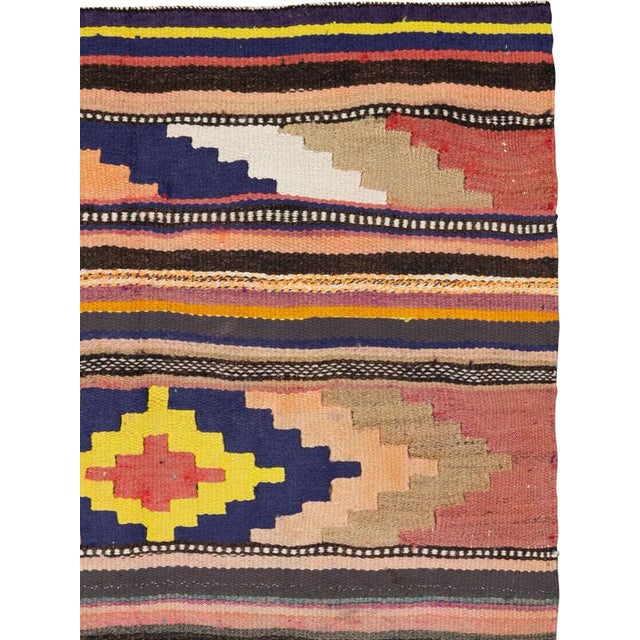 This mid-20th century Persian flatweave kilim rug presents a vibrant expression of tribal artistry through bold geometry...