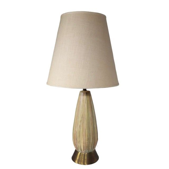 Diminutive Mid Century table lamp having an oblong ceramic body with polychrome textured surface, on a brass plinth base....