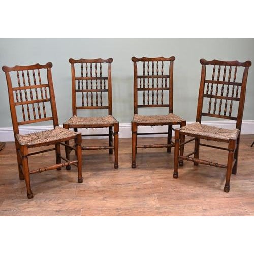 Attractive set of four country dining chairs with tall spindle backs and woven rush seats. Shaped crest rails with rounded...