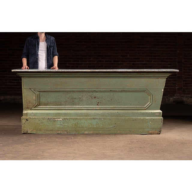 Long-form general store counter featuring a hand-applied zinc work surface over a painted wooden base with paneled front....