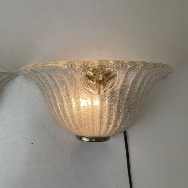 Set of two sconces in clear murano glass, made with the graniglia technique, which produces a granular, textured effect...