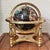 A fine black globe inlaid with semiprecious gemstones; including mother of pearl, amethyst, african jade, tiger's eye,...