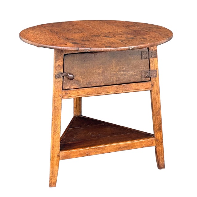 A handsome large English cricket table of patinated oak from the Georgian Era - featuring the traditional round or...