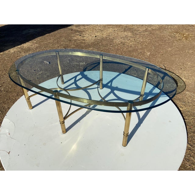This vintage Mid Century Cocktail Labarge Style Brass and Glass Oval Coffee Table from the 1970s exudes Hollywood Regency...