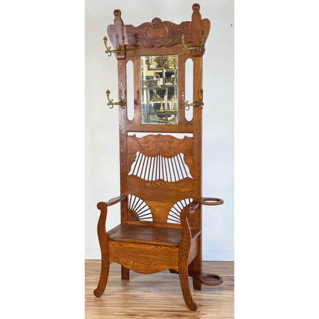 Antique Early 20th Century American oak hall tree with hinged storage bench seat and ornate iron butterfly coat hangers....