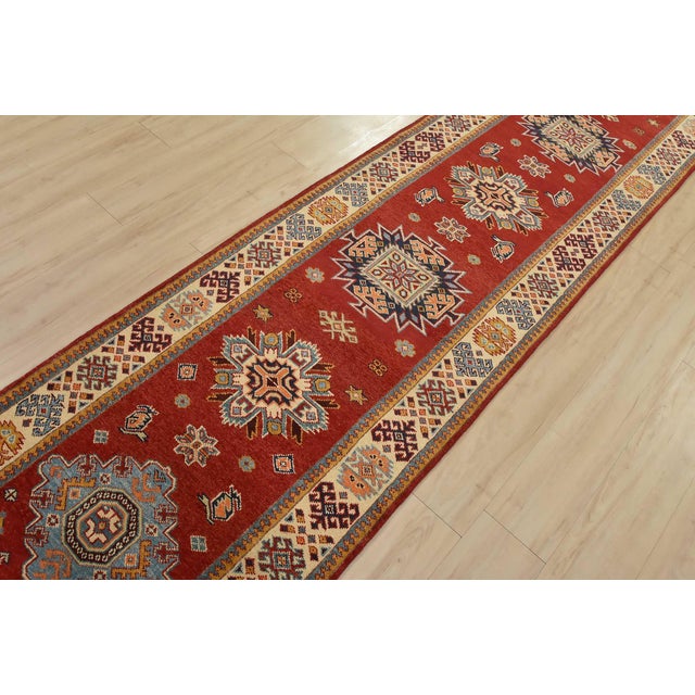 A tribal Caucasian Kazak runner hand-knotted with fine wool on a cotton foundation. This rug features a row of geometric...