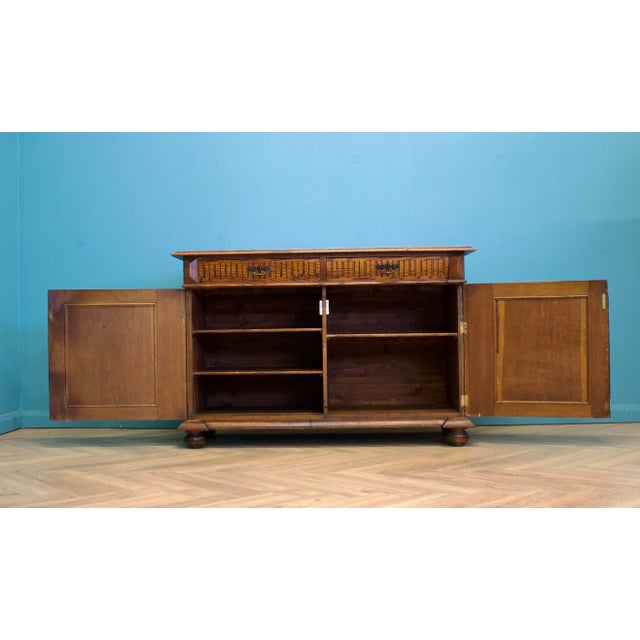 Early 20th century continental oak sideboard with carved detailing, pierced panel doors and turned bun feet. Fitted with...