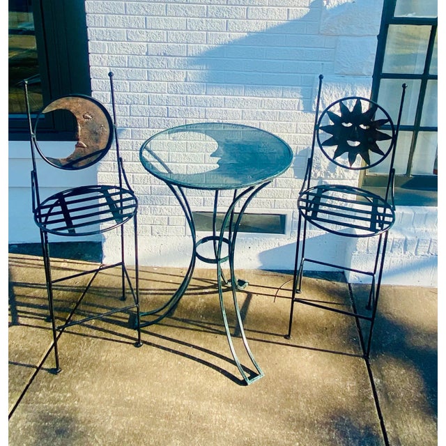 An exquisite set of two Art Deco wrought iron indoor or patio bar chairs and round high top table. The circular shaped...