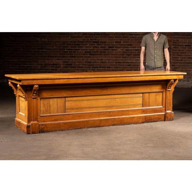 Substantial antique general store counter constructed in solid oak with a paneled facade, projecting work surface, and...