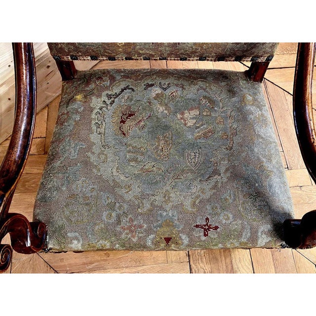 Louis XIII period armchair in molded and carved walnut, upholstered with a stitched tapestry resting on four moving legs...