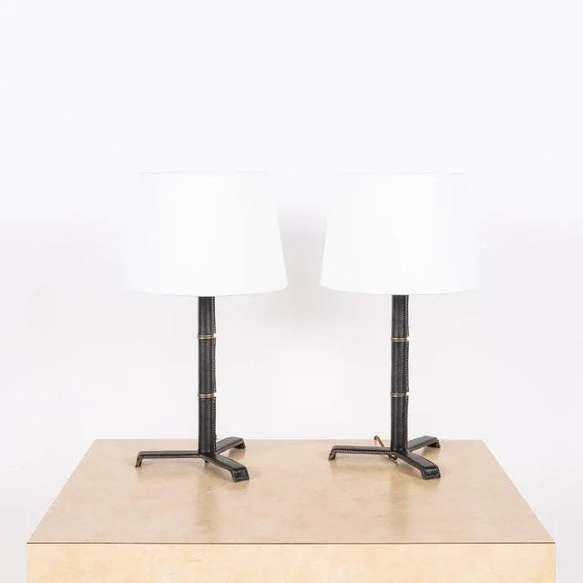 Introducing the 'Sellier' French modernist-style stitched black leather table lamps by Design Frères. Crafted from premium...