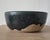American studio pottery bowl with a low cylindrical profile and dramatic black glaze flowing irregularly over a warm,...