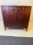 Modernist Cherry Toned Walnut Two Door Cabinet With Four Hinged Panel Front. There is a Lock Present And A Center Shelf....