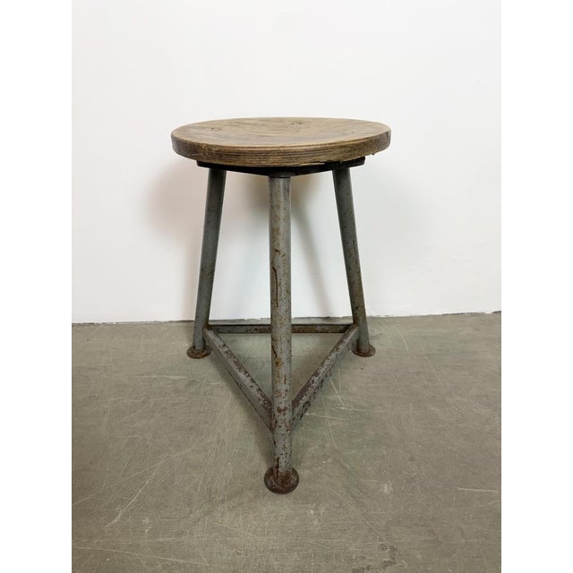 Vintage Industrial factory stool made in former Czechoslovakia during the 1960s It features a wooden seat and a grey iron...