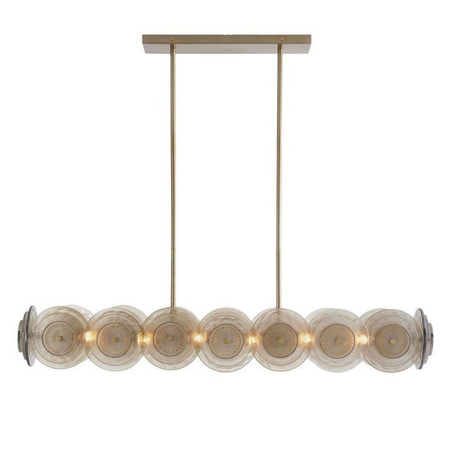 A modern take on Art Deco, the Kinlee is composed of a series of handcrafted glass discs on a linear frame with 12 lights...
