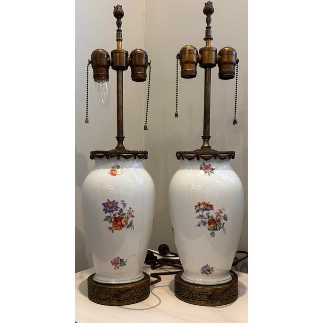 Elegant and timeless, this matched pair of vintage porcelain urn lamps features romantic classical figural scenes and...
