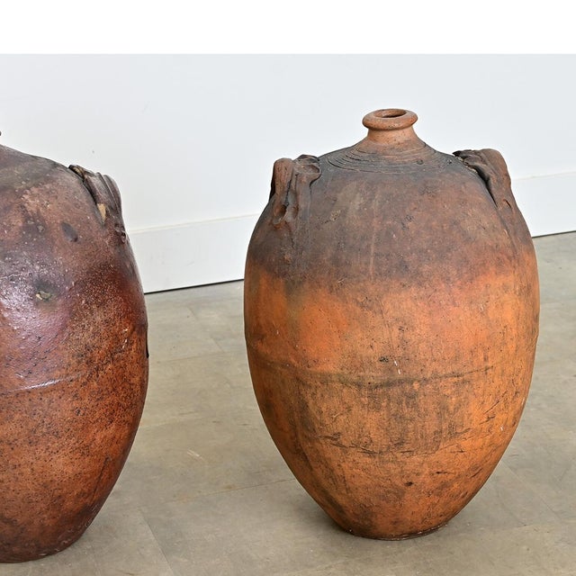 A pair of enormous 19th century French stoneware cruches traditionally used as a bottle or demijohn to transport and store...