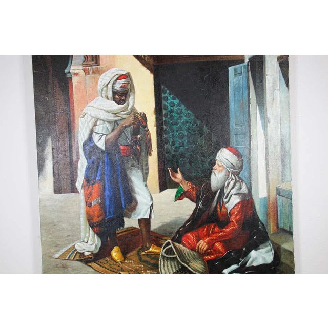 Moroccan Orientalist oil on canvas painting of a 19th century Moroccan market scene with an old men seating on a carpet...