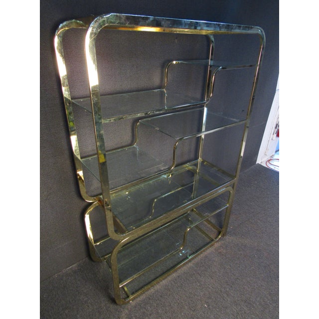 Mid-Century Modern bookcase with sliding base. Brass frame and glass shelving.